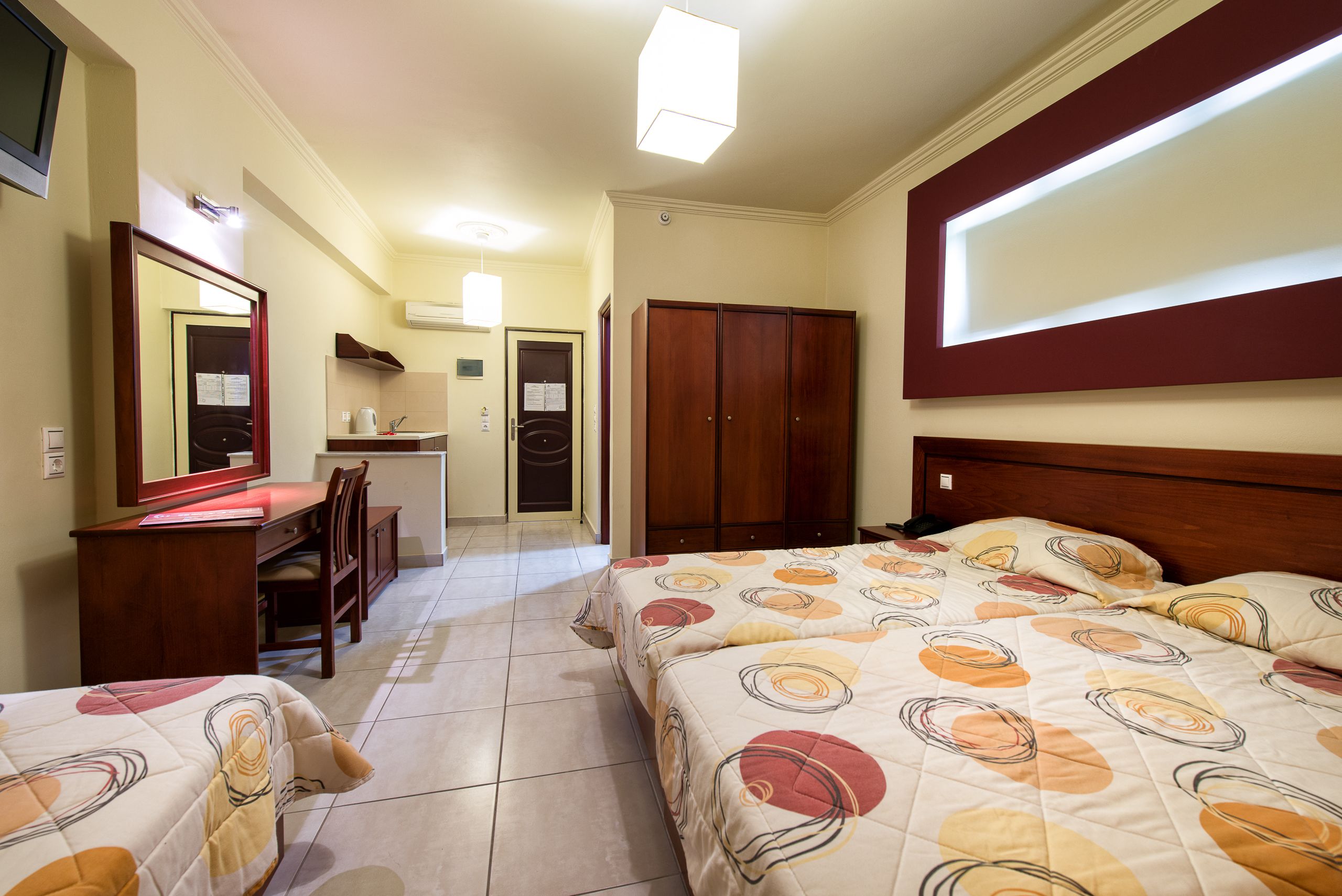 Une chambre d’hôtel avec deux lits, un bureau, une chaise, une armoire et un miroir.