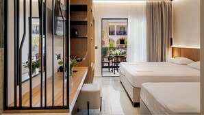 A modern hotel room with a wooden desk, a TV, a balcony with plants, and two beds. - Canadian (Zakynthos)