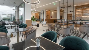 A modern interior with a bar area, seating with round tables, and a large potted plant. - Canadian (Zakynthos)