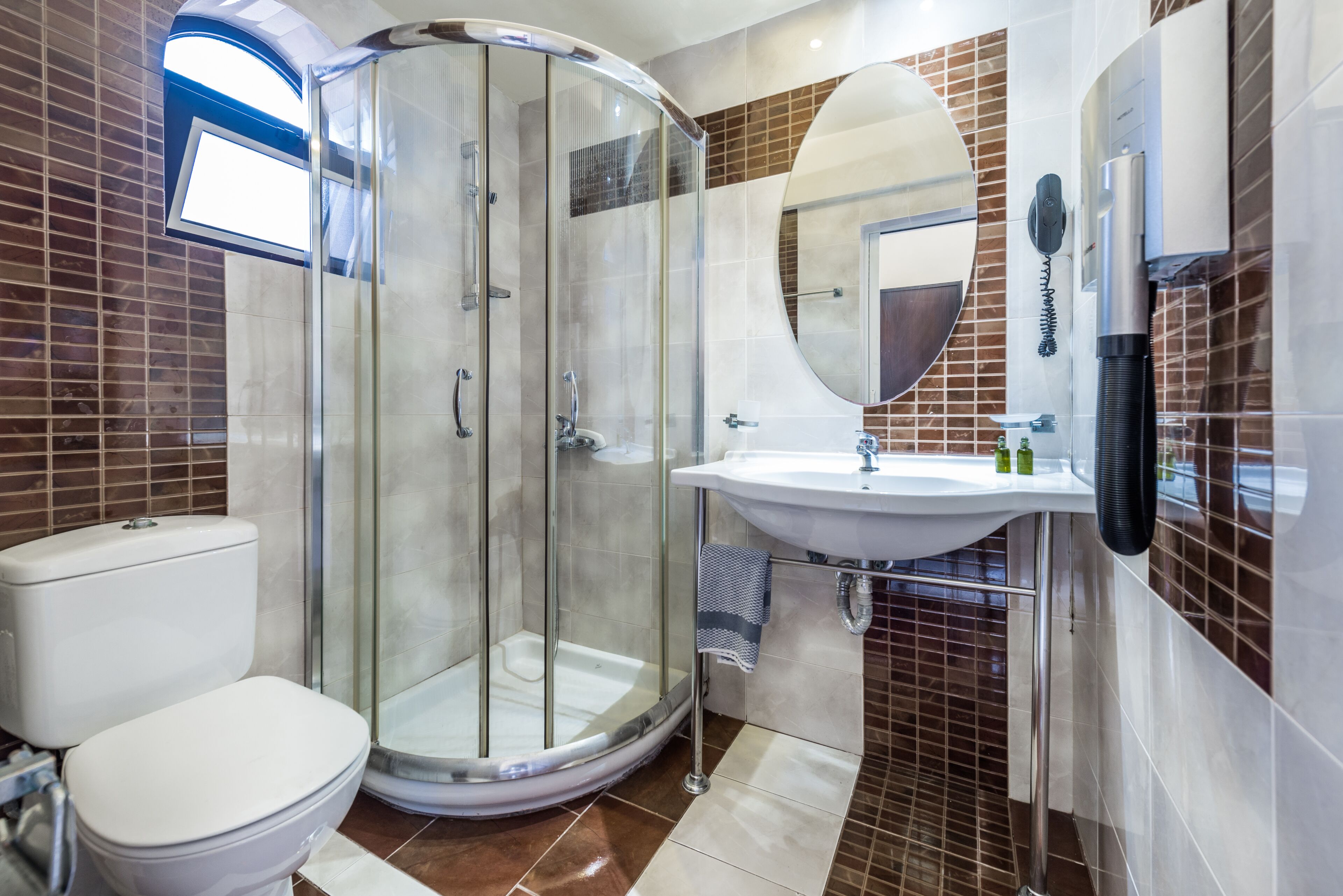 A modern bathroom with a glass-enclosed shower, a white toilet, a sink, and a mirror.