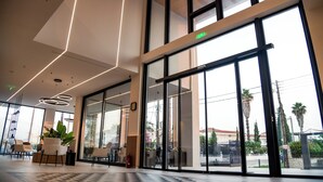 A modern lobby with large glass doors, a check-in counter, and seating area with potted plants. - Canadian (Zakynthos)