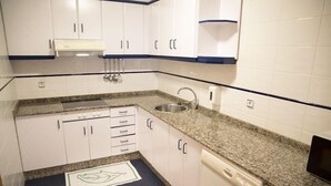 A compact kitchen with white cabinets, a granite countertop, a built-in dishwasher, and a stainless steel sink. - Alda Castelao (Vilagarcia de Arousa)