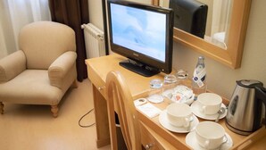 A hotel room with a bed, a desk with a computer, a chair, and a coffee table with cups and a kettle. - Alda Castelao (Vilagarcia de Arousa)