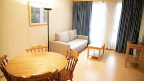 A living room with a round wooden dining table, a sofa, and a small side table. - Alda Castelao (Vilagarcia de Arousa)