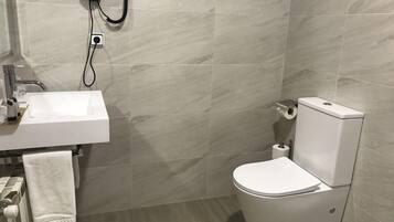 Un baño moderno con lavamanos, inodoro y toallero blancos.