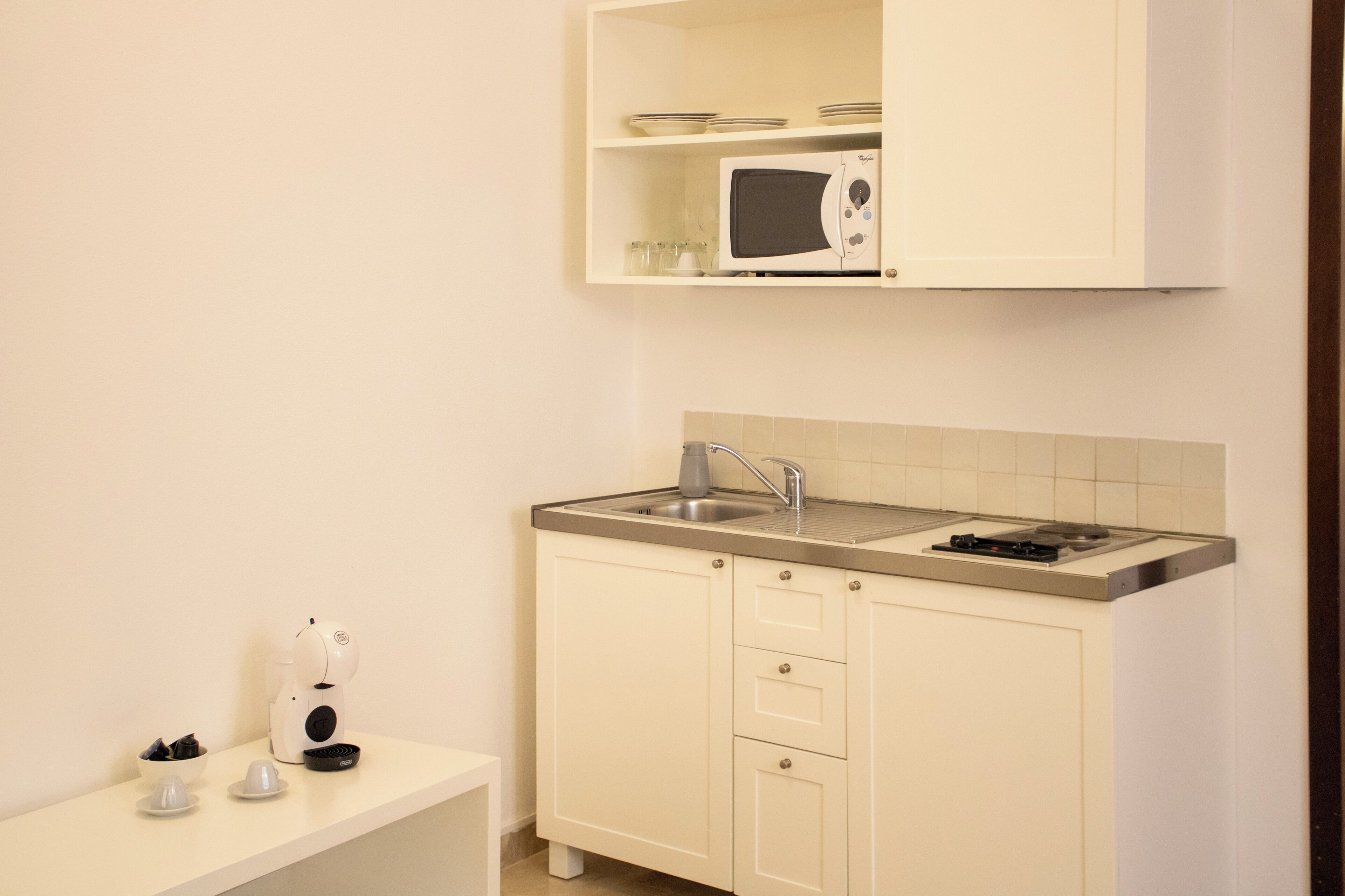 A small kitchenette with a microwave, sink, and a coffee maker.