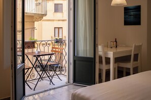Habitació d'hotel amb balcó, taula de dinar i llit.
