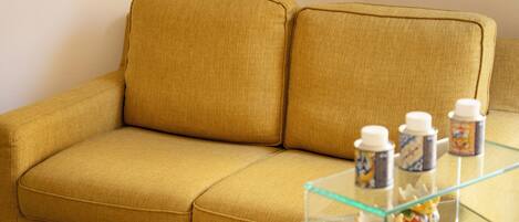 A mustard-colored sofa with a glass coffee table in front.