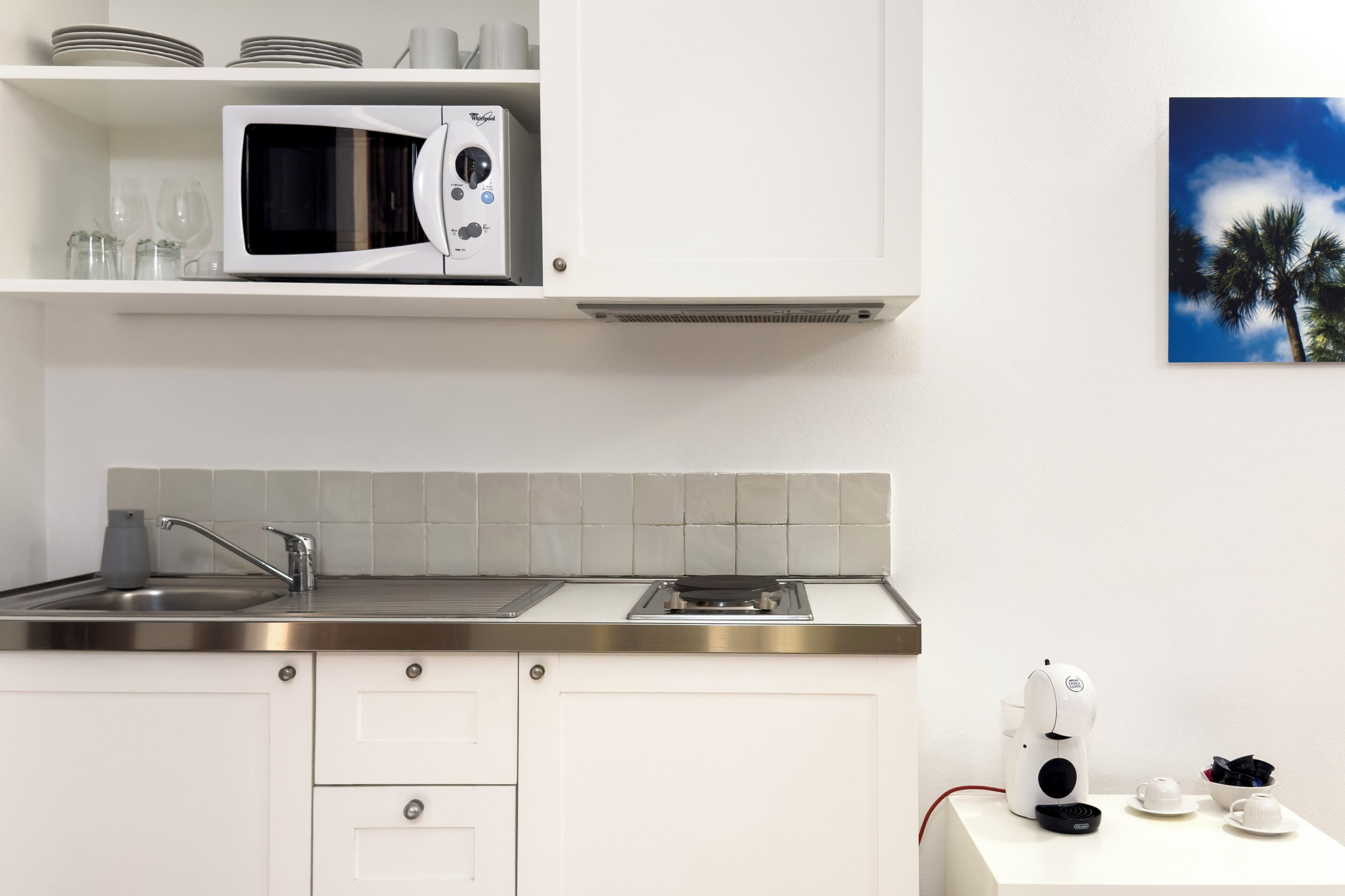 Una cocina moderna con microondas, lavamanos y cafetera.
