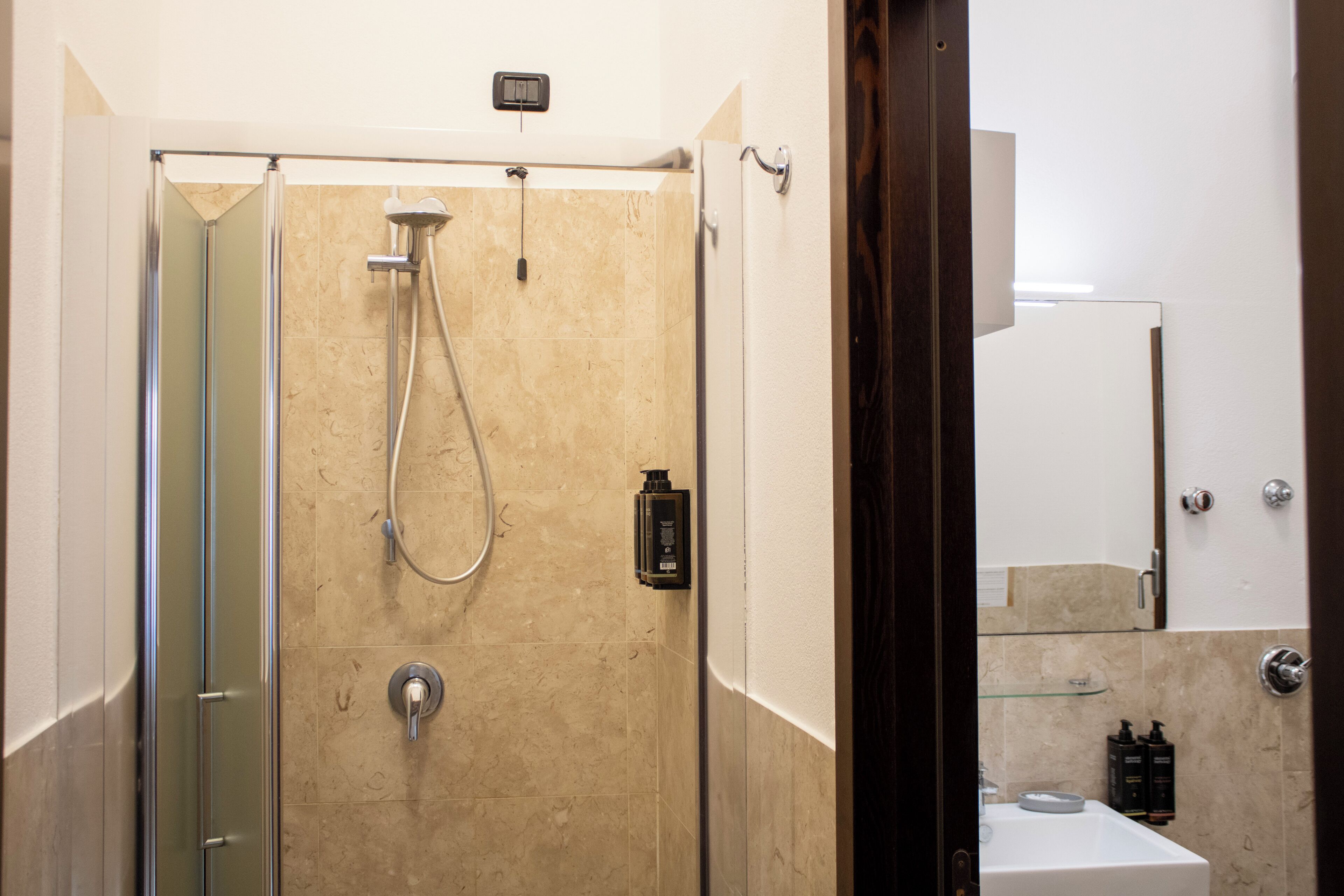 Un baño moderno con ducha separada por vidrio, un lavamanos y un espejo.