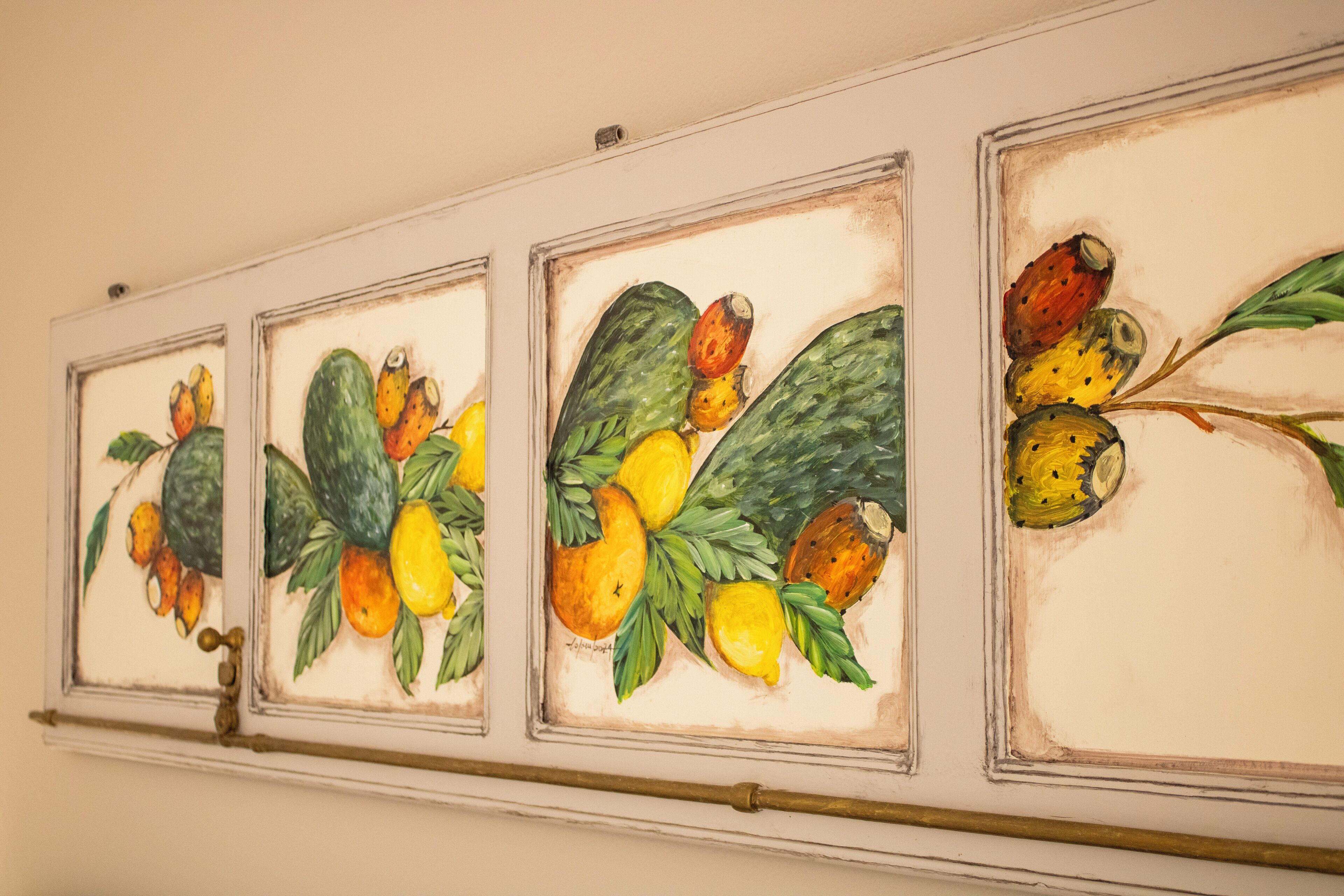 Una pared con tres cuadros enmarcados de frutas y verduras.