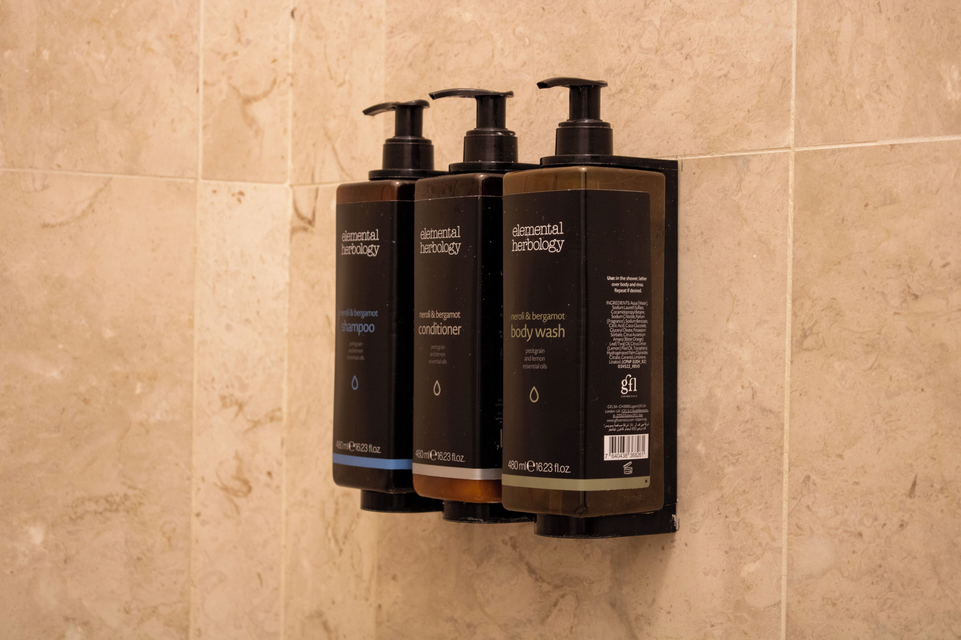 Three bottles of Elemental Herology products on a wall.