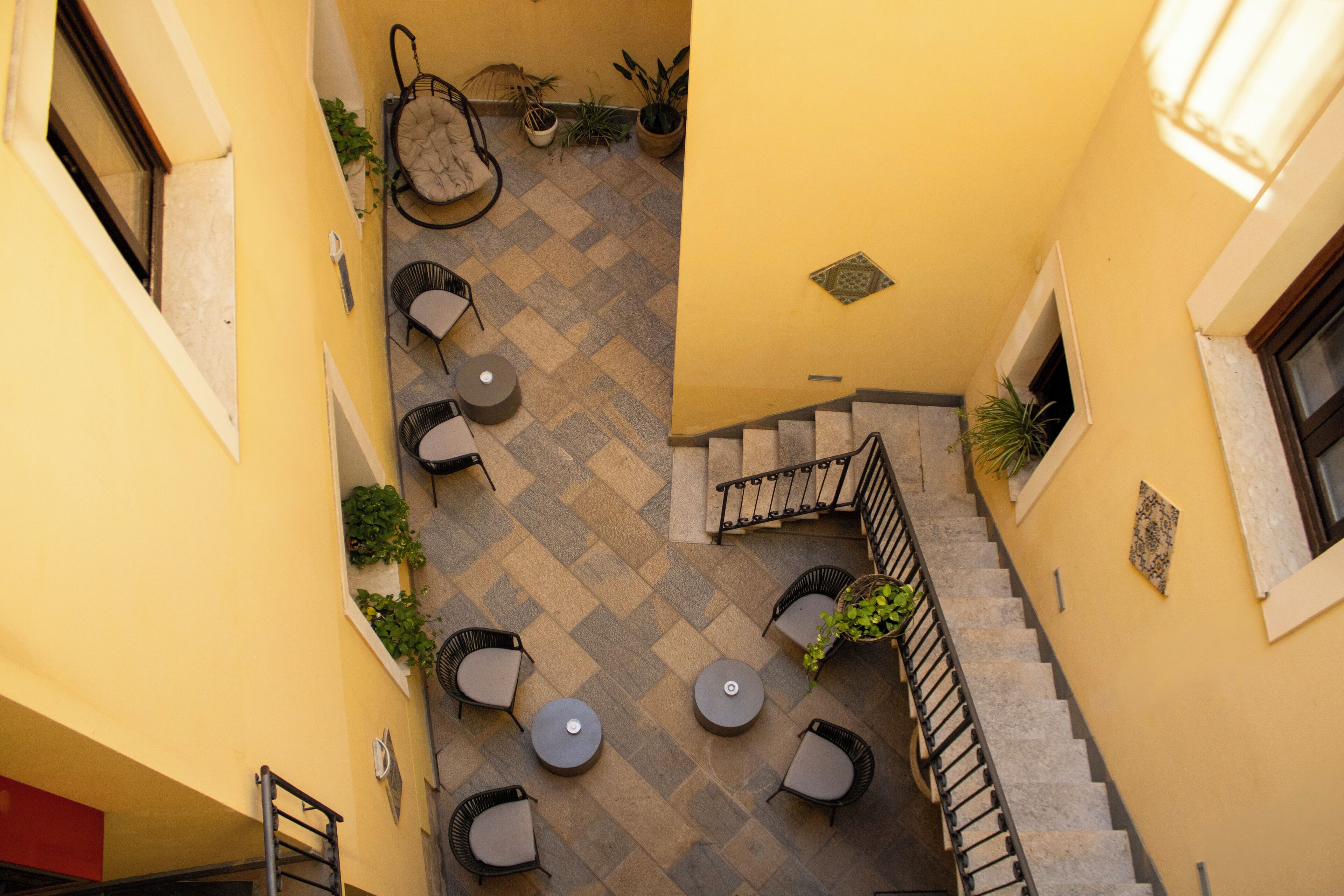 A courtyard with outdoor seating, a staircase, and potted plants.