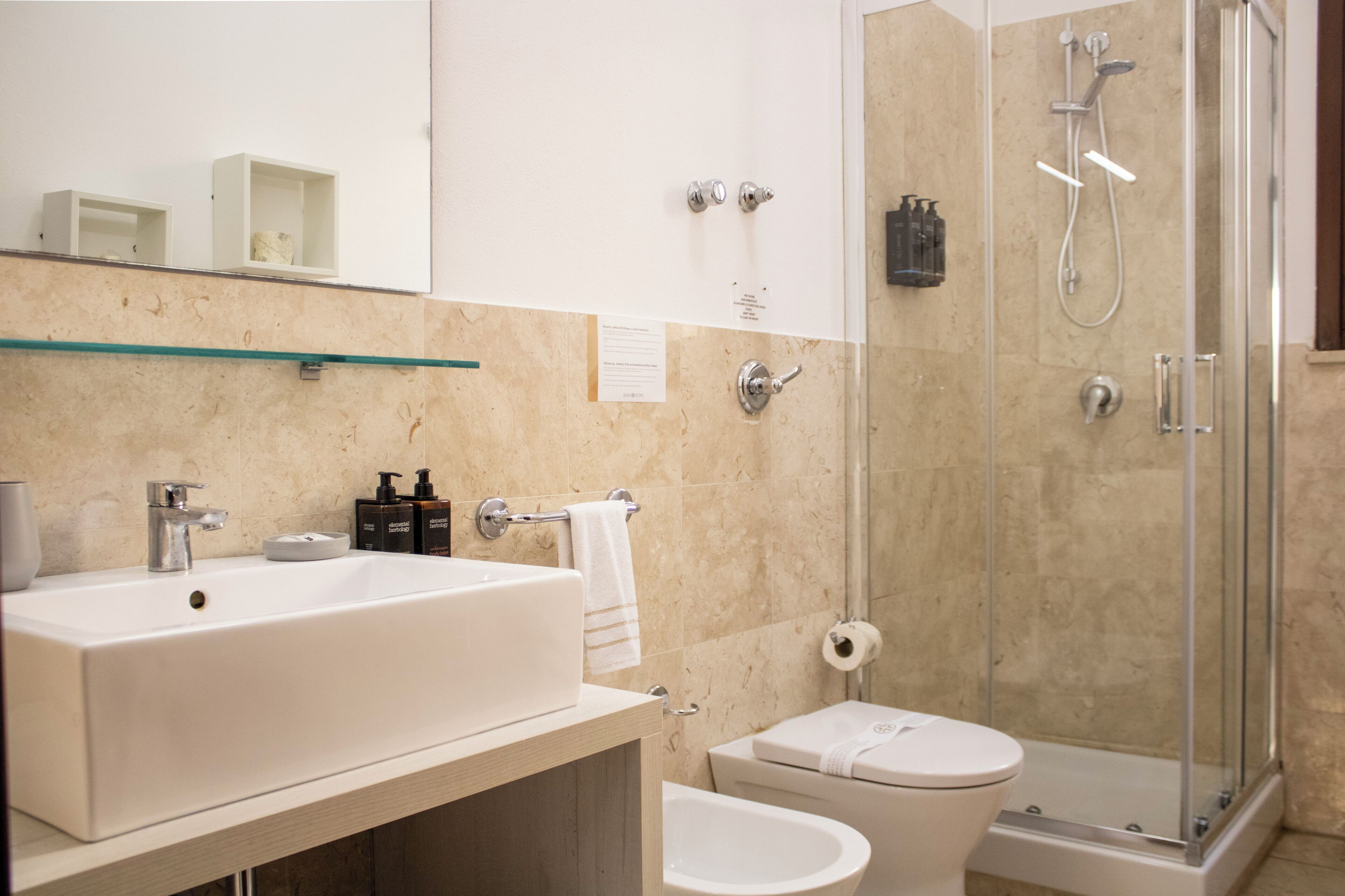 A bathroom with a large white sink, a toilet, and a glass-enclosed shower area.