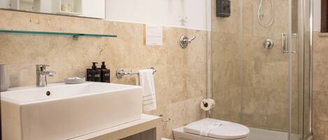 A bathroom with a large white sink, a toilet, and a glass-enclosed shower area.