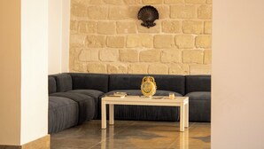 Una sala de estar moderna con una pared de piedra, un sofá modular gris oscuro y una mesa de centro blanca.