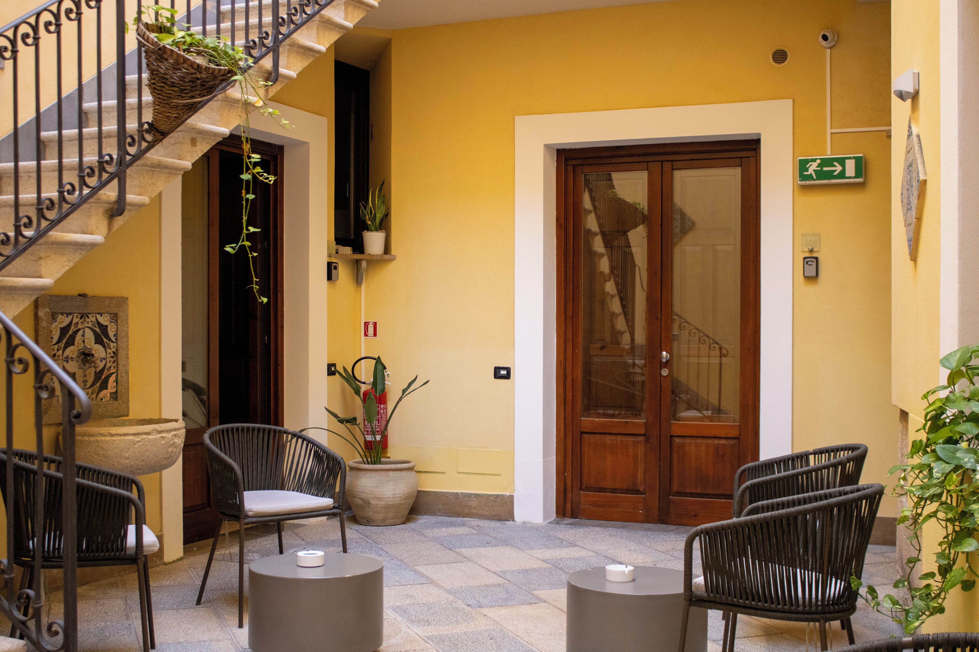 A courtyard with wicker chairs, a potted plant, and a wooden door.
