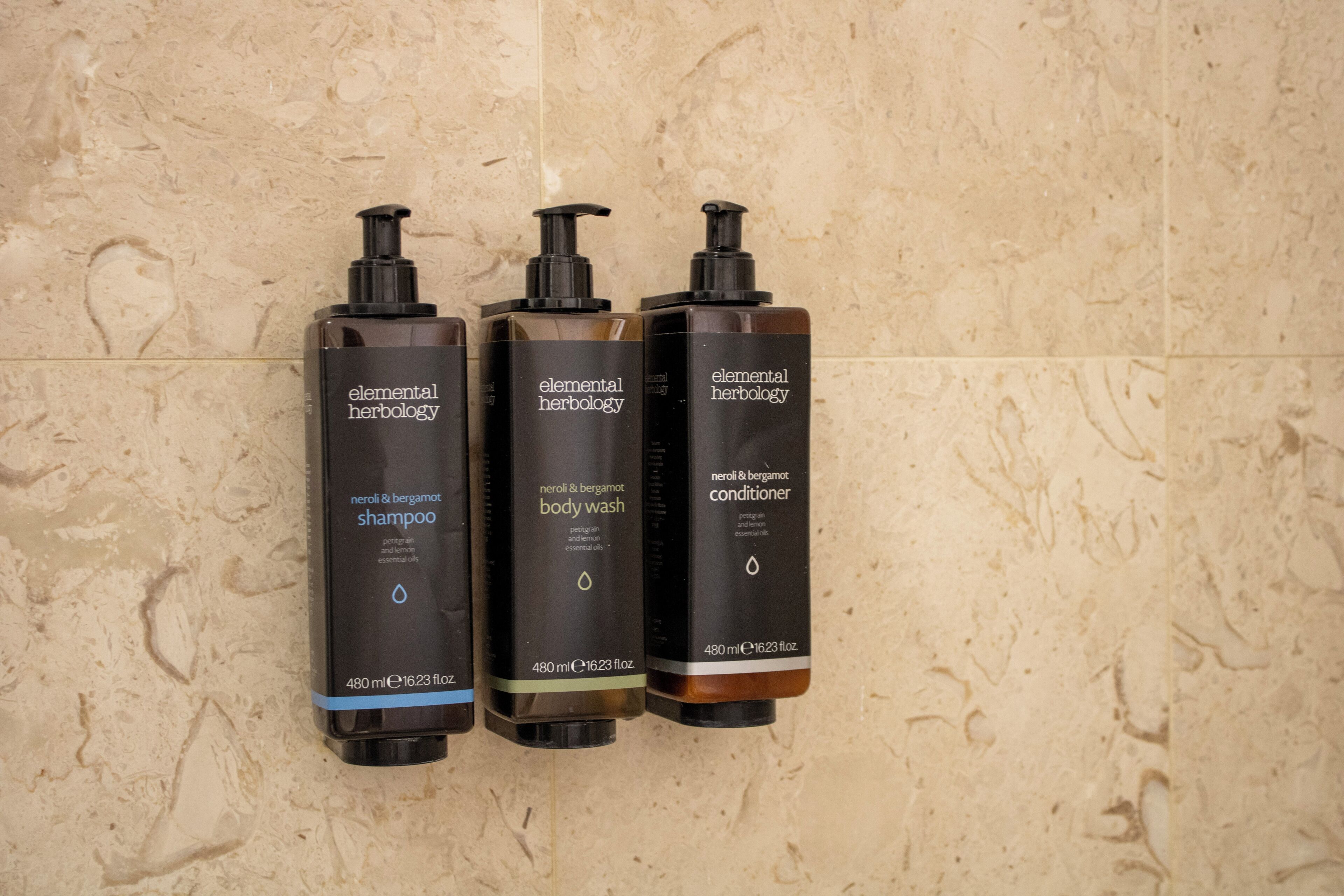 Three bottles of Elemental Herbology products on a tiled wall.
