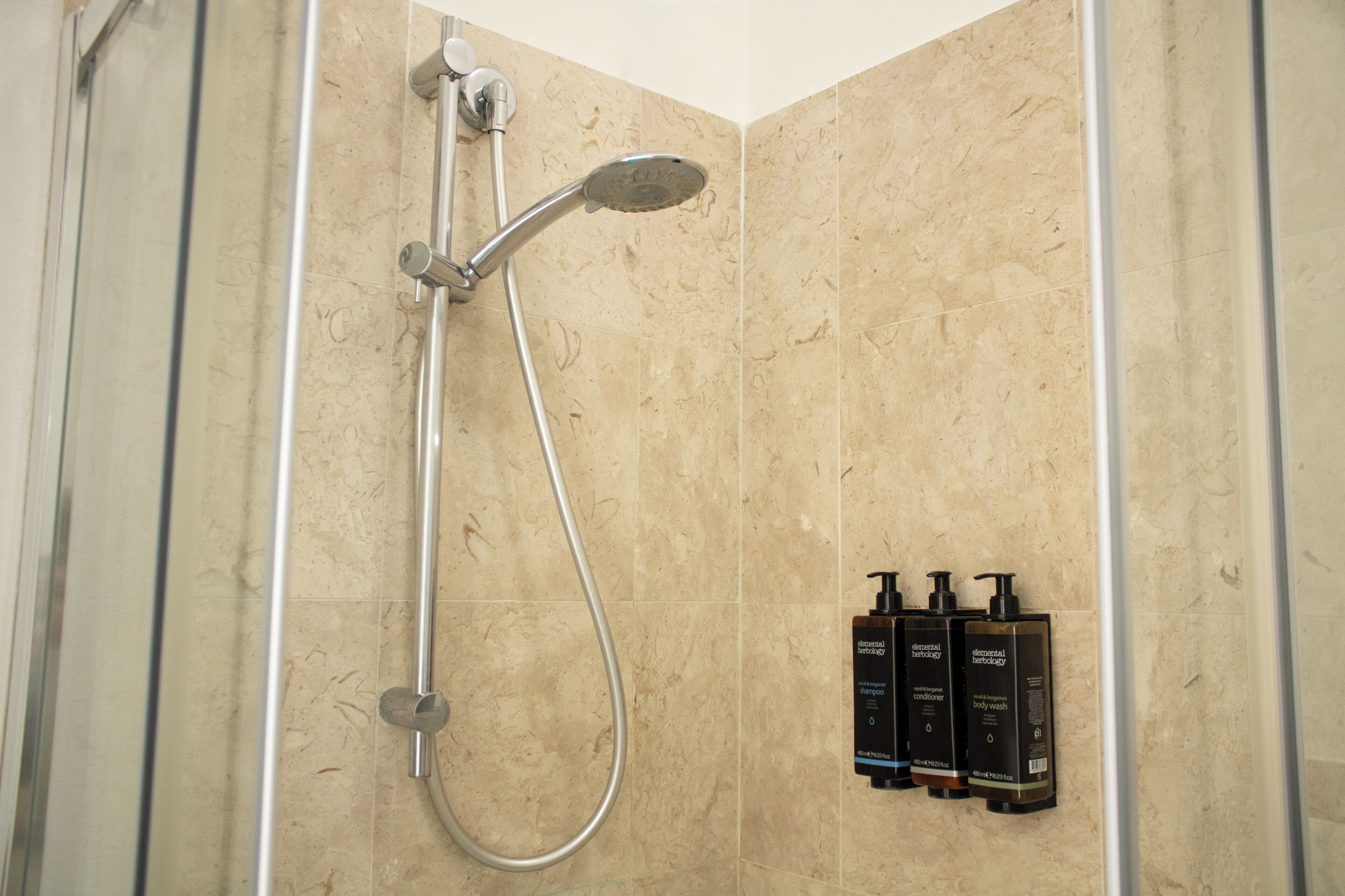A shower with a handheld showerhead and a wall-mounted control valve.