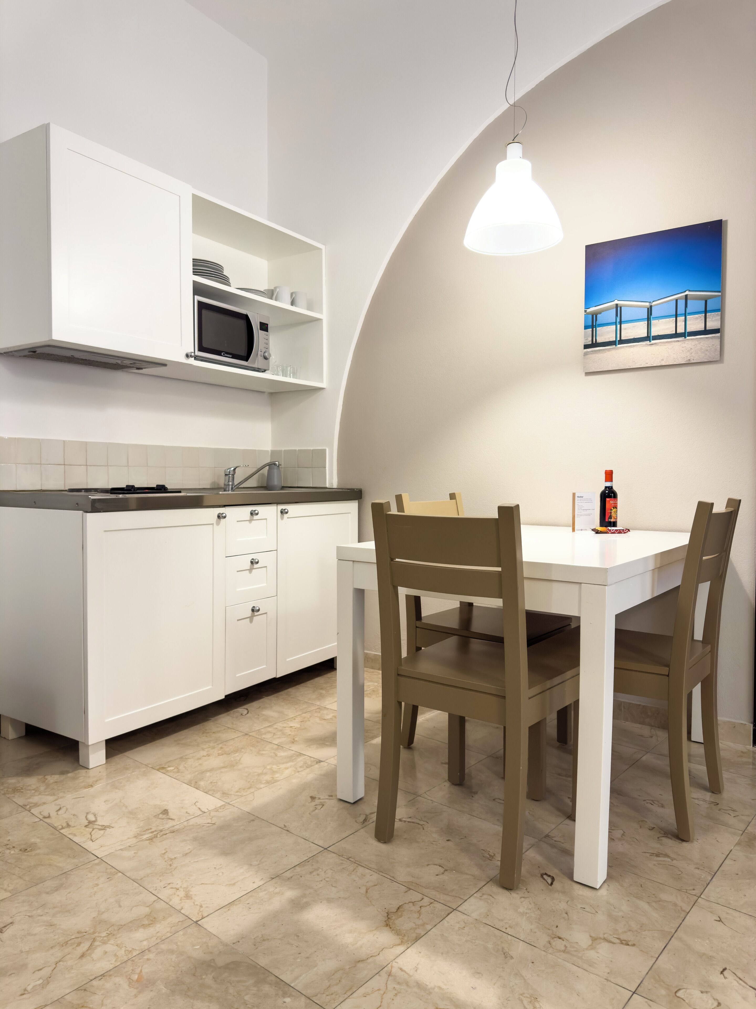 Una cocina moderna con armarios blancos, microondas integrado y una mesa de comedor con sillas.