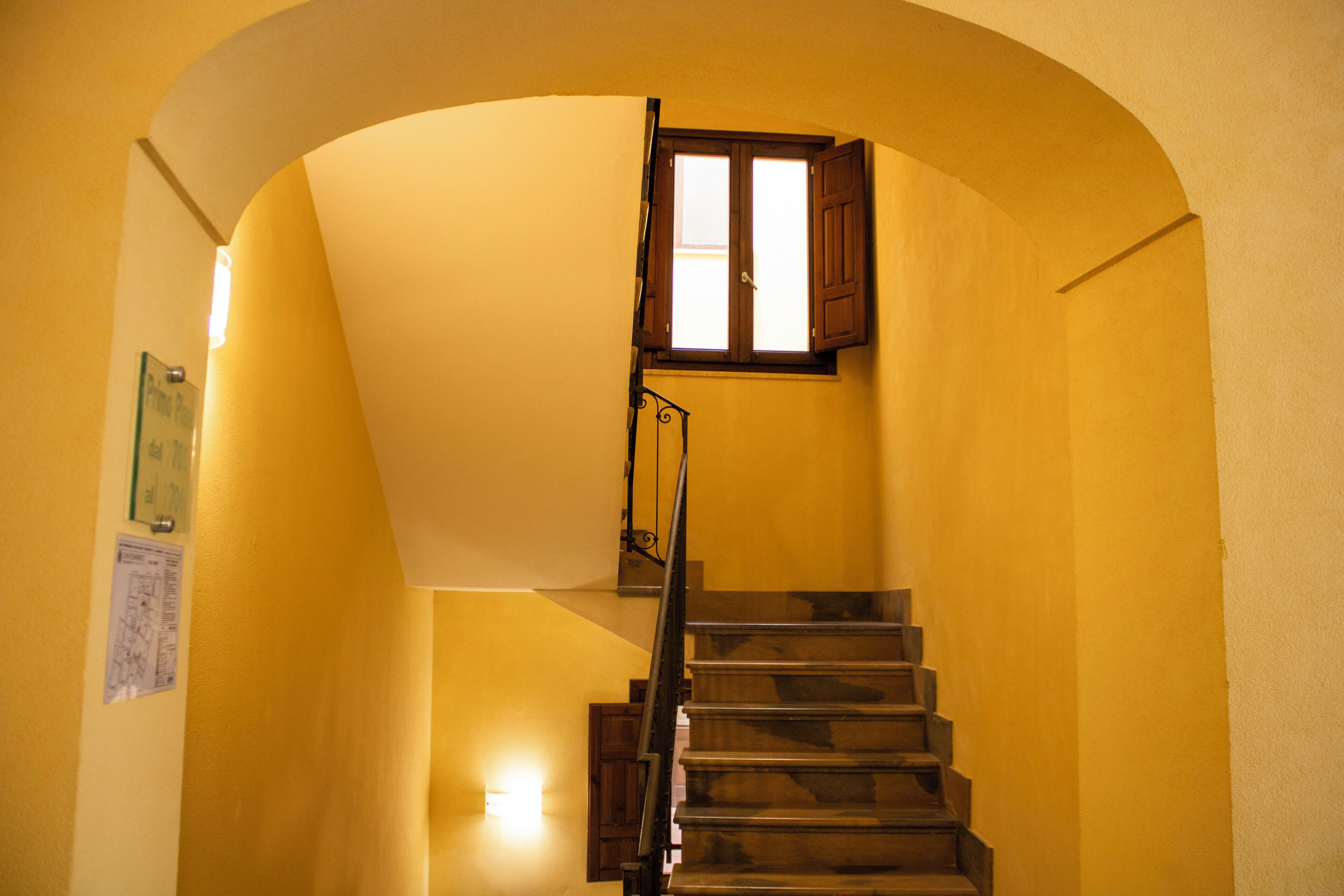 A staircase with a wooden handrail and a window with wooden shutters.