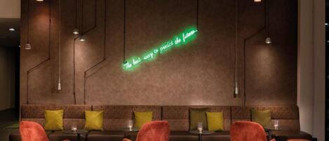 A modern lounge area with a neon sign, sofas, and red chairs.