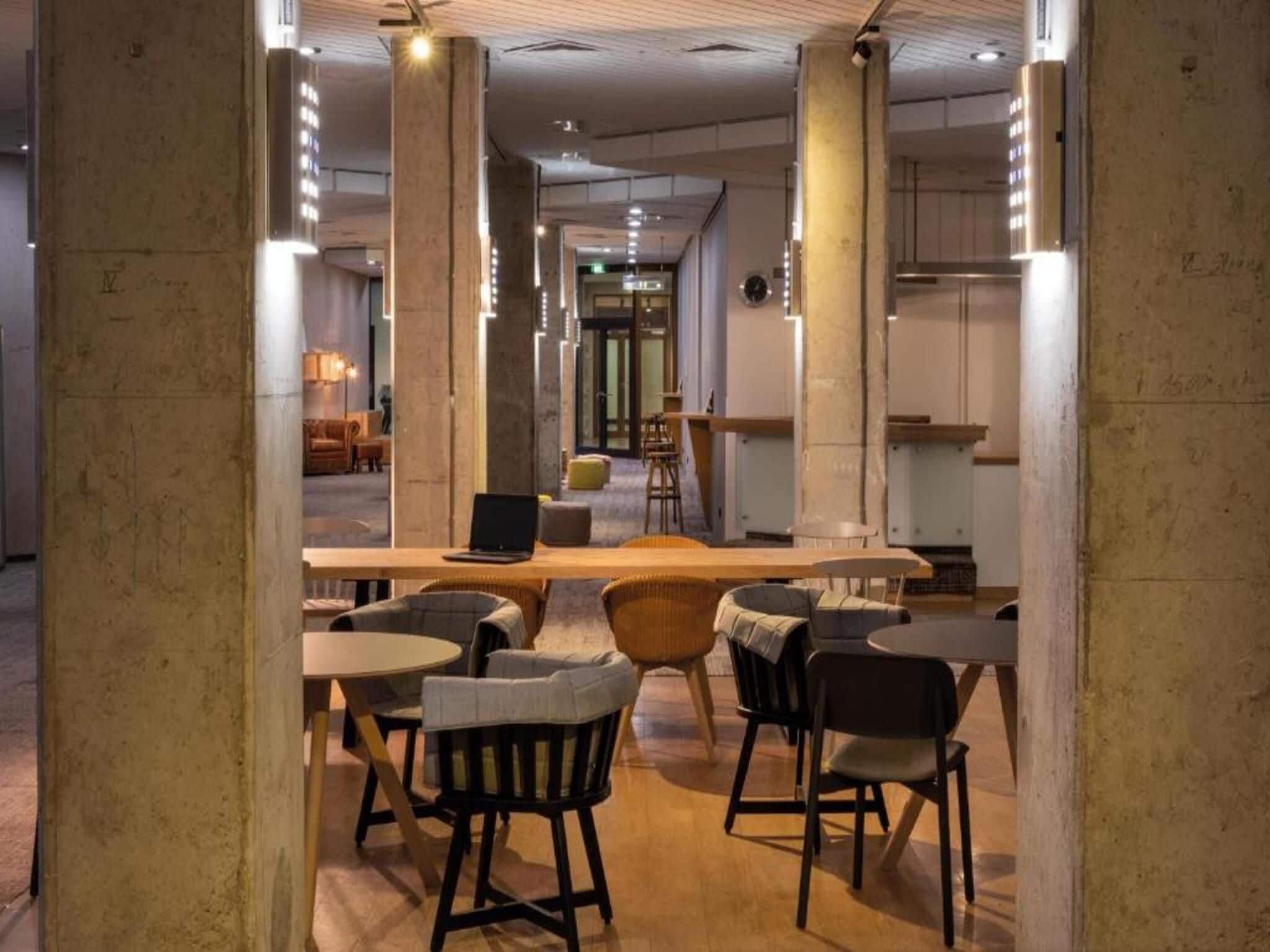 A modern interior with a central bar area, multiple seating arrangements, and a visible entrance to another room.