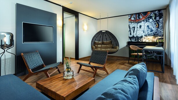 Un salon moderne avec un téléviseur à écran plat, deux fauteuils, une table basse et un canapé.