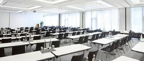 Un amplio salón de conferencias con varias mesas y sillas dispuestas en filas.