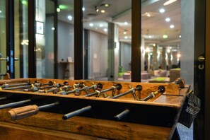 A foosball table in a well-lit indoor space with glass walls and a modern interior design.