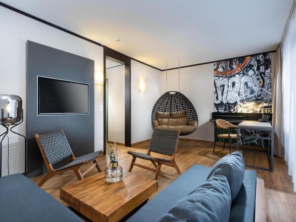 A modern living room with a wooden coffee table, two armchairs, a sofa, a hanging chair, and a dining area with a table and chairs.