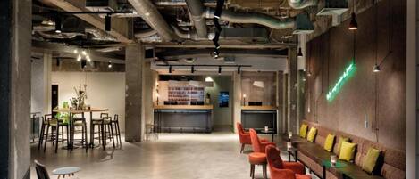 Un espace intérieur comprenant un espace central ouvert, des zones aménagées pour s’asseoir et un bar.
