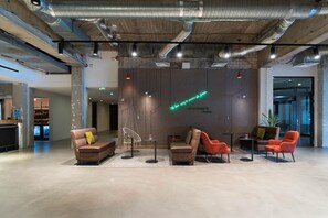Relax in a stylish lounge area with a sofa, armchair, and chairs, surrounded by a unique neon sign and pendant lights.