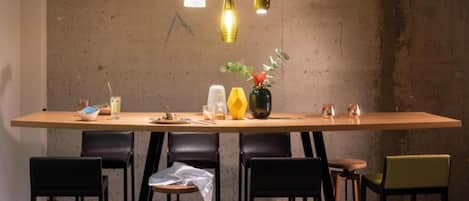 A dining area with a long table, six chairs, and hanging pendant lights.