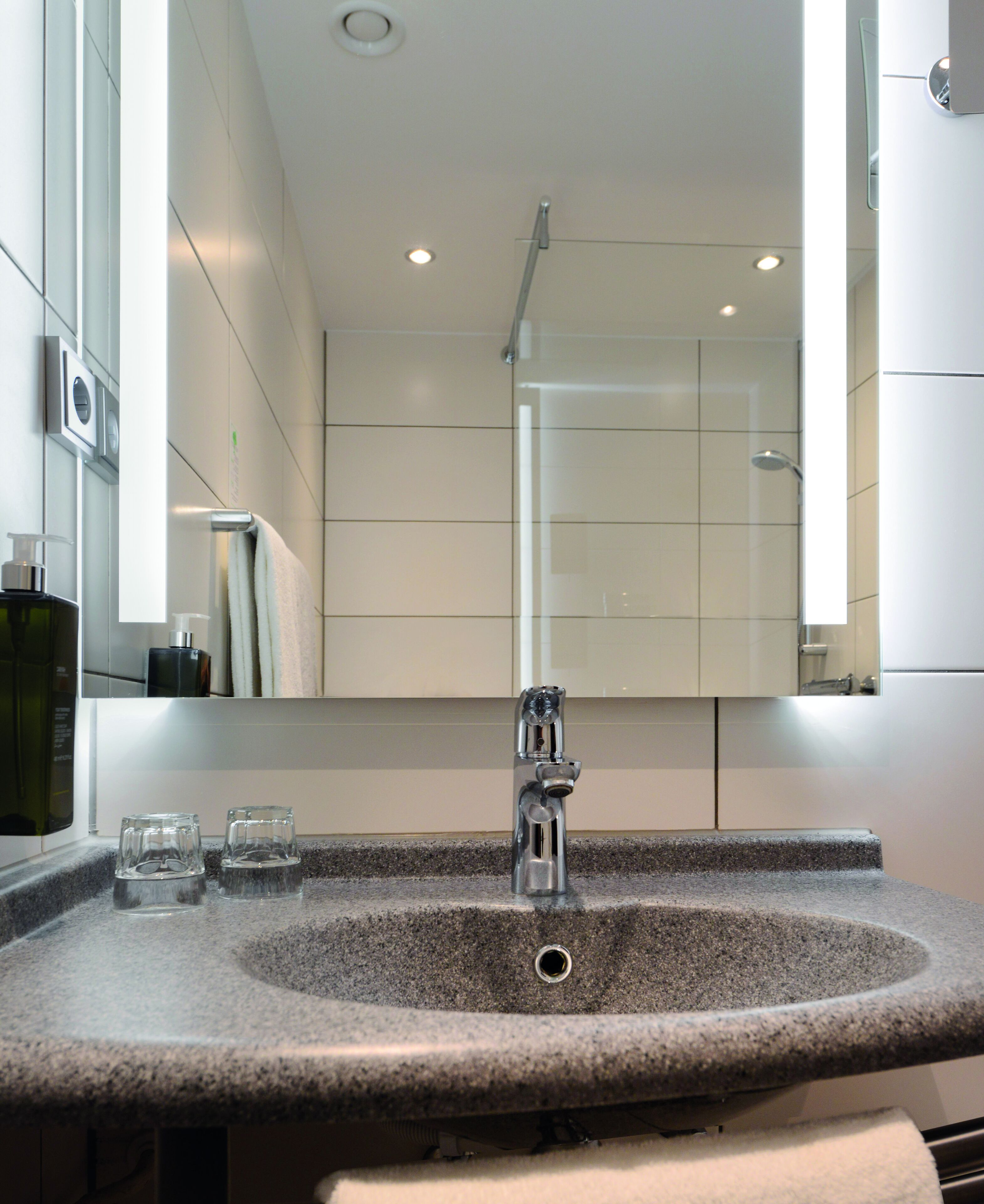 A modern bathroom with a granite sink, a mirror, and a shower.