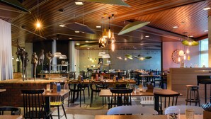 Un restaurant moderne doté d’un plafond en bois, de luminaires suspendus et de différents types de sièges, notamment des tables et des chaises.