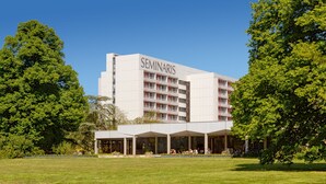 Un bâtiment moderne, avec l’inscription « SÉMINAIRES » sur la façade, entouré d’une végétation luxuriante et d’une pelouse bien entretenue.