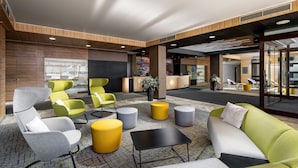 A modern lobby with a mix of seating options including sofas, chairs, and ottomans. There is a reception desk in the background. - Pinia Hotel & Resort (Spindleruv Mlyn)