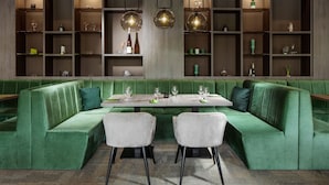 A green upholstered booth with a table set for dining, surrounded by shelves with various items. - Pinia Hotel & Resort (Spindleruv Mlyn)
