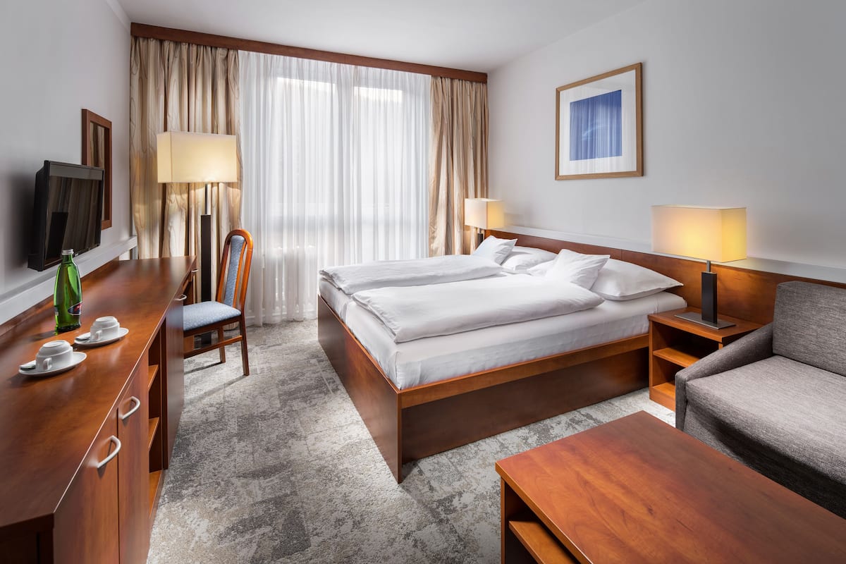 Ein Hotelzimmer mit einem Bett, einem Schreibtisch mit Stuhl, einem Fernseher und einem Sofa.