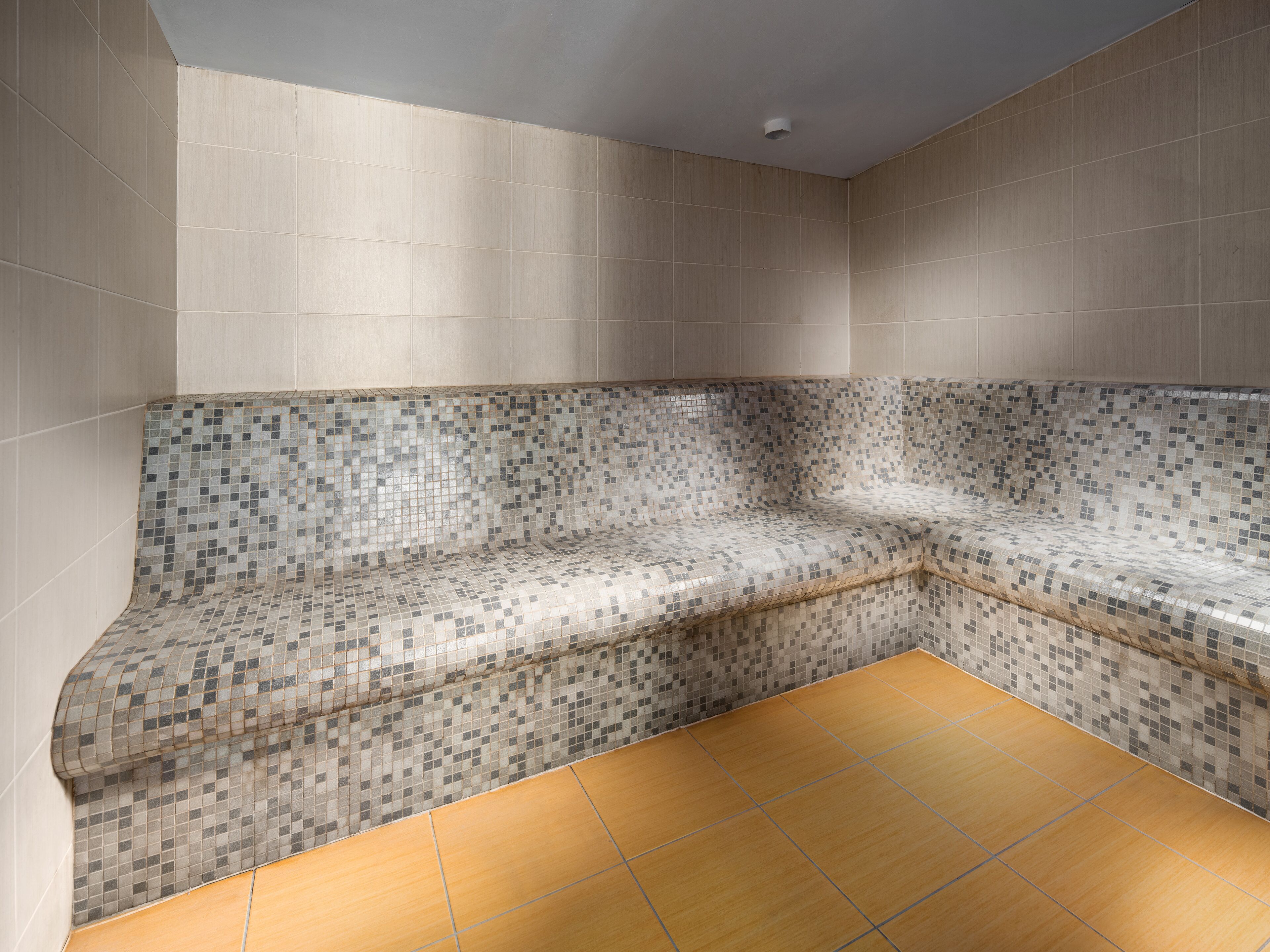 A corner seating area with mosaic tile walls and a wooden floor.
