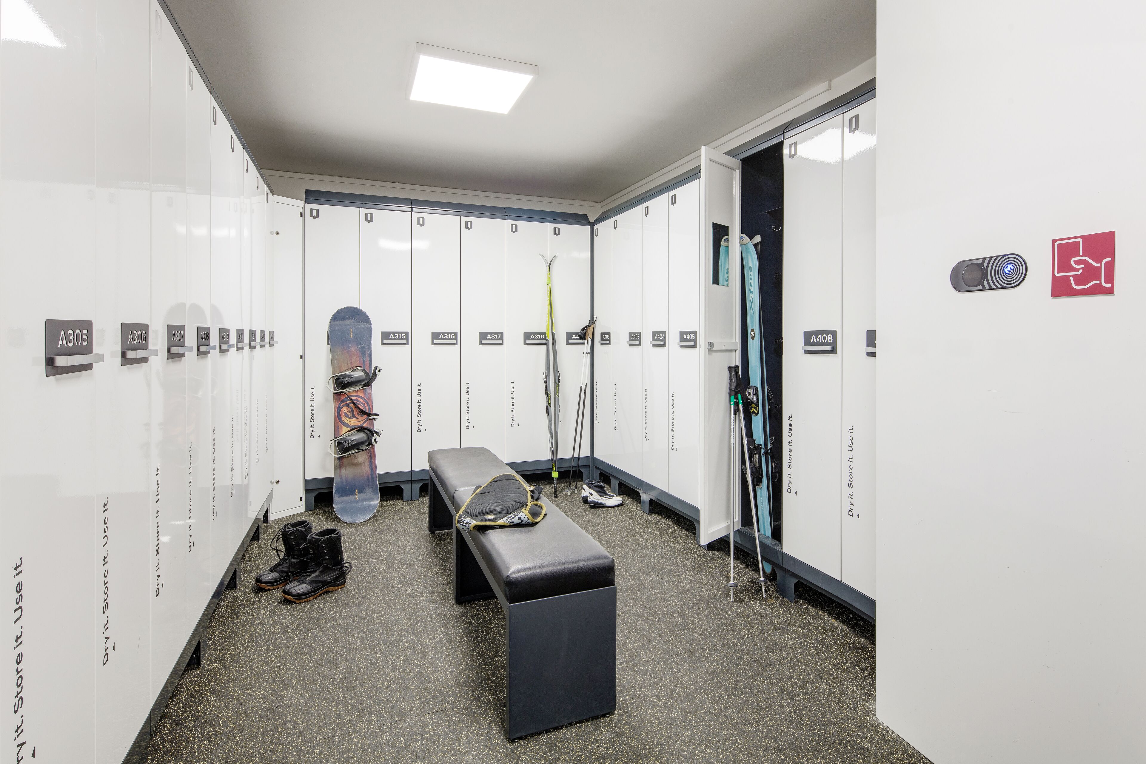 A locker room with multiple lockers, a bench, and various sports equipment.