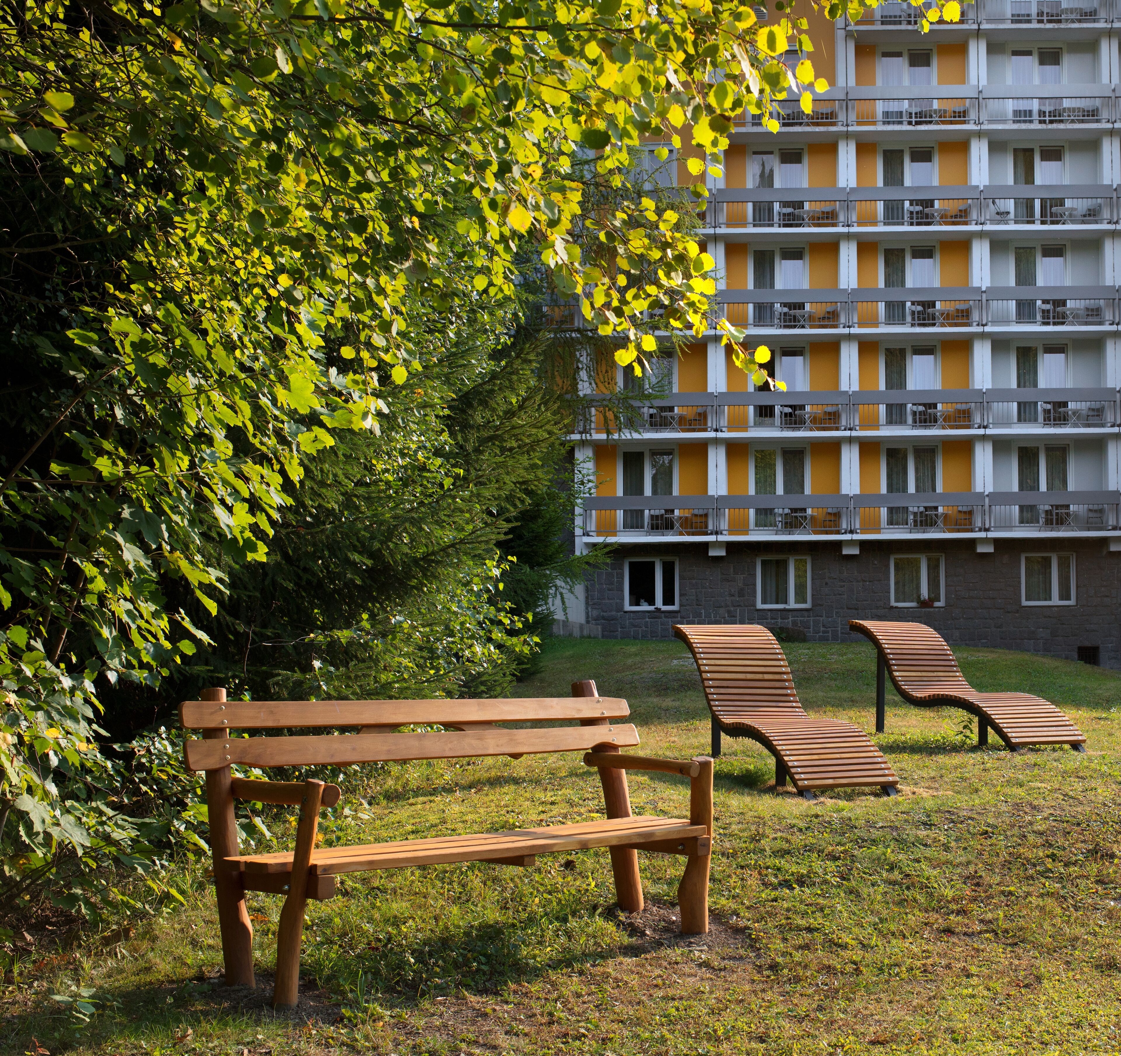 Un parque con un banco de madera y dos sillones de descanso.