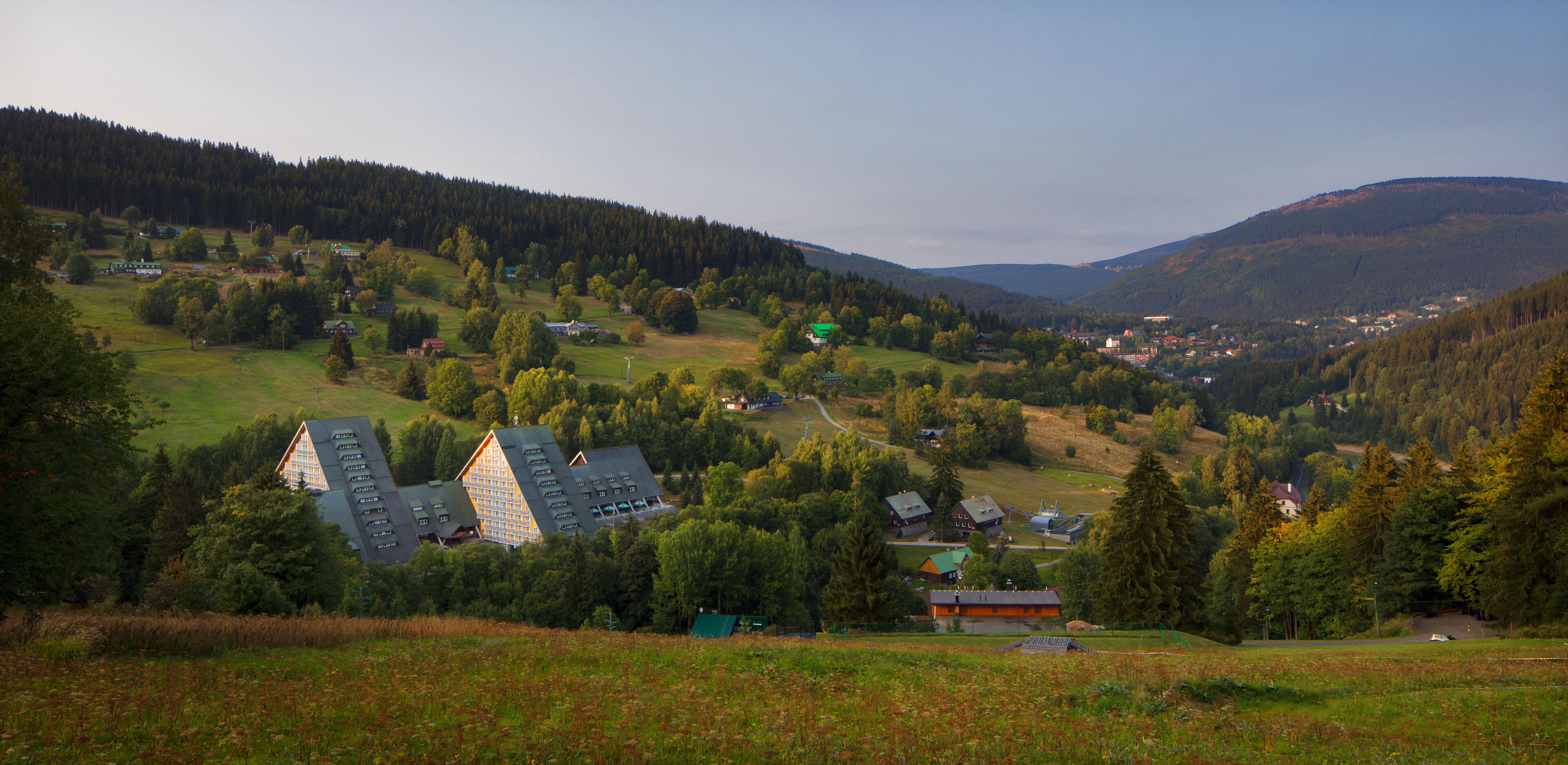 A rural landscape with houses surrounded by trees and hills.