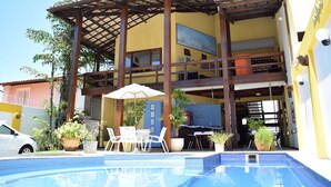 Um edifício de dois andares com piscina, área de estar ao ar livre e vasos de plantas.