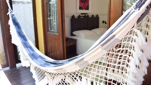 Uma rede em um quarto com uma cama, uma porta de madeira e um quadro na parede.