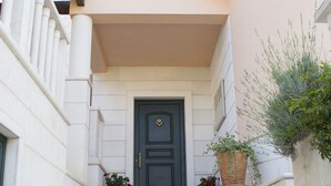 A set of white stone steps leading to a dark door with a brass knocker, flanked by two potted plants with flowers. - Villa Lavandula (Trogir)