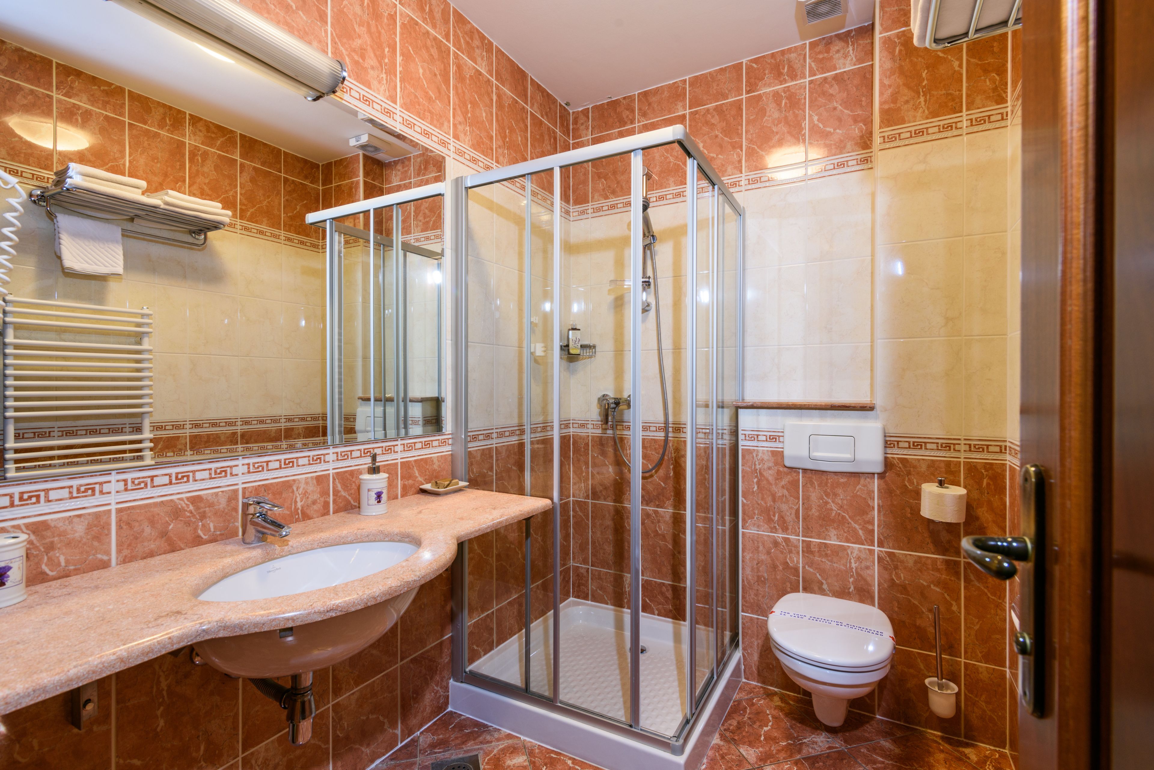 A bathroom with a glass-enclosed shower, a sink, and a toilet.