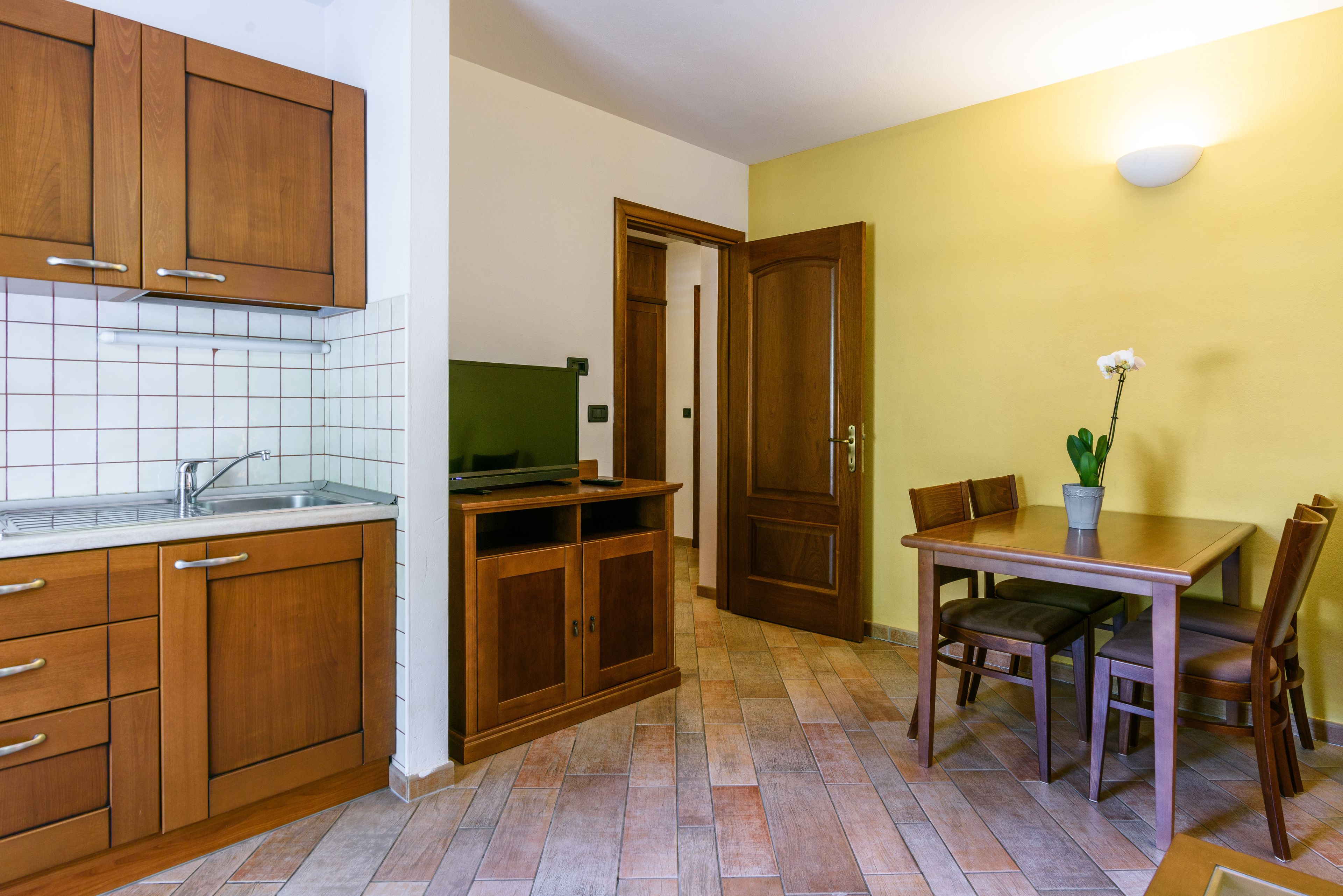 Une cuisine avec des meubles de rangement en bois, un évier et un coin repas comprenant une table et des chaises.