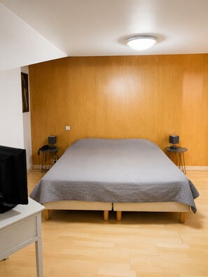 A room with a bed, two bedside tables, a desk with a computer, and a wall-mounted light fixture. - Auberge La Crémaillère (Villandraut)
